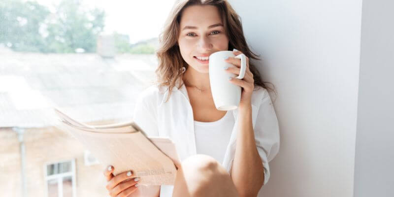 Iloinen nainen juo kahvia